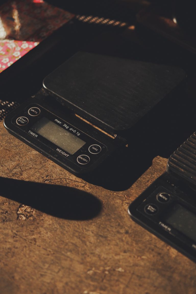 A digital kitchen scale on a rustic brown surface, showing various weighing options.