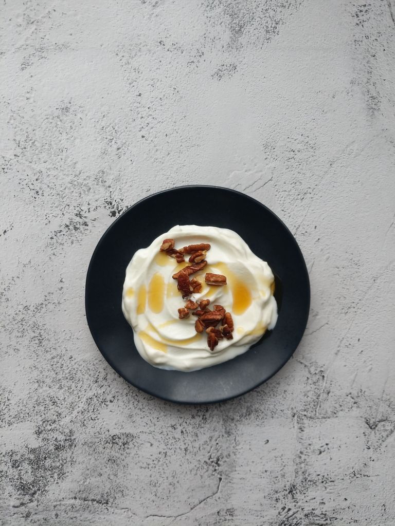 A mouthwatering plate of Greek yogurt topped with pecans and drizzled with honey.