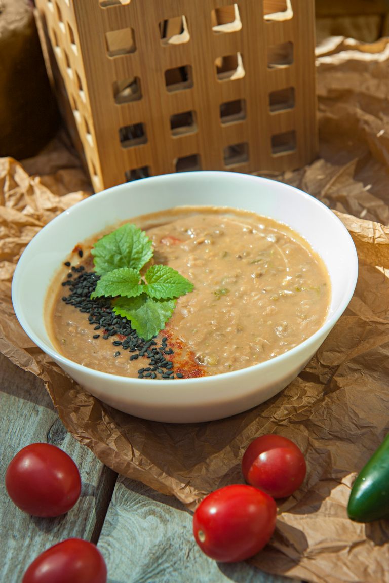 Delicious lentil soup garnished with basil served in a white bowl, perfect for a healthy meal.