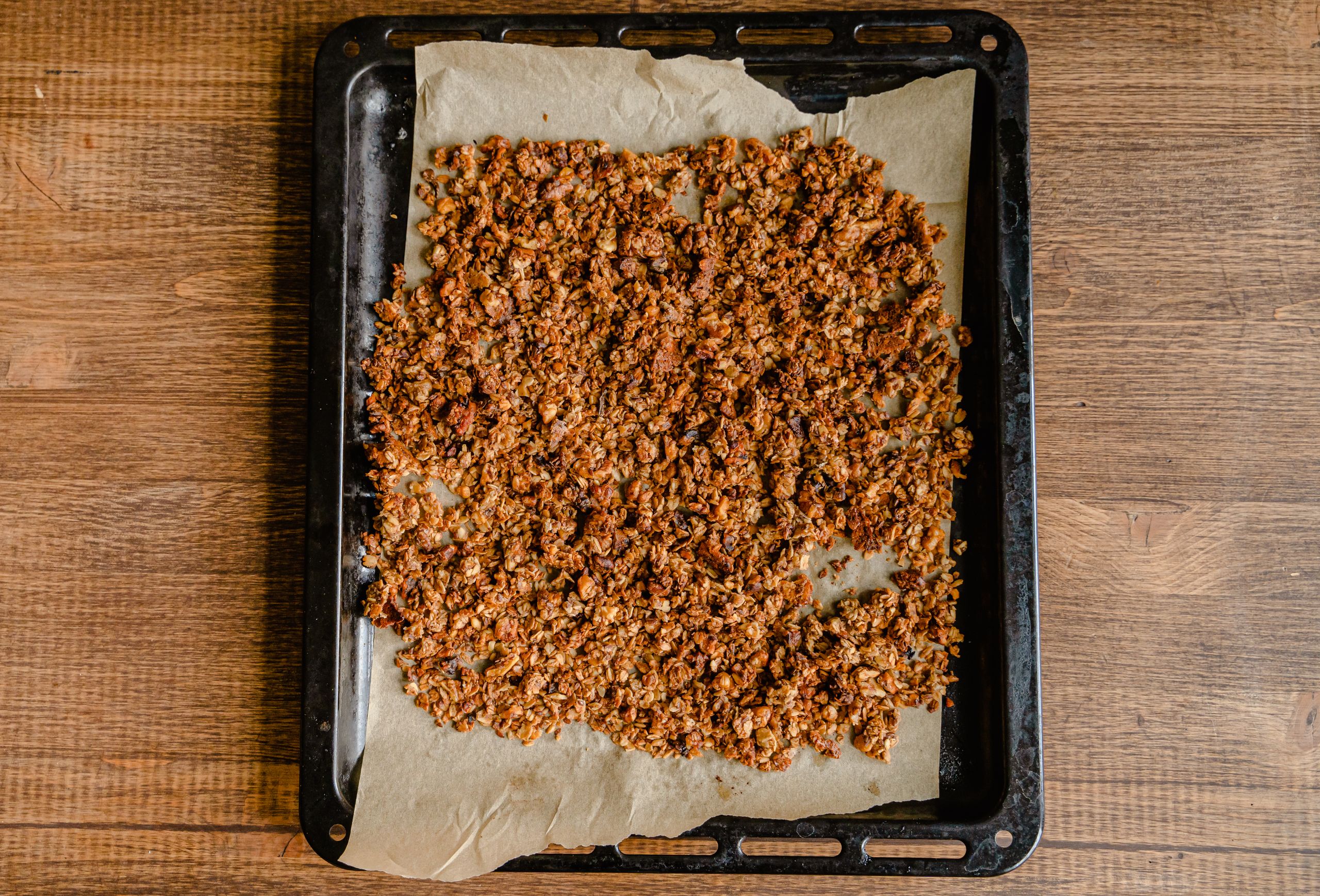Freshly baked granola cooling on a baking tray lined with parchment paper.